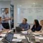 Team in a conference room watching a presenter explain an SAP S/4HANA Roadmap on a whiteboard.
