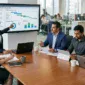 A diverse team of SAP consultants and business professionals collaborating around a conference table in a modern office while reviewing S/4HANA digital transformation analytics on large monitors.